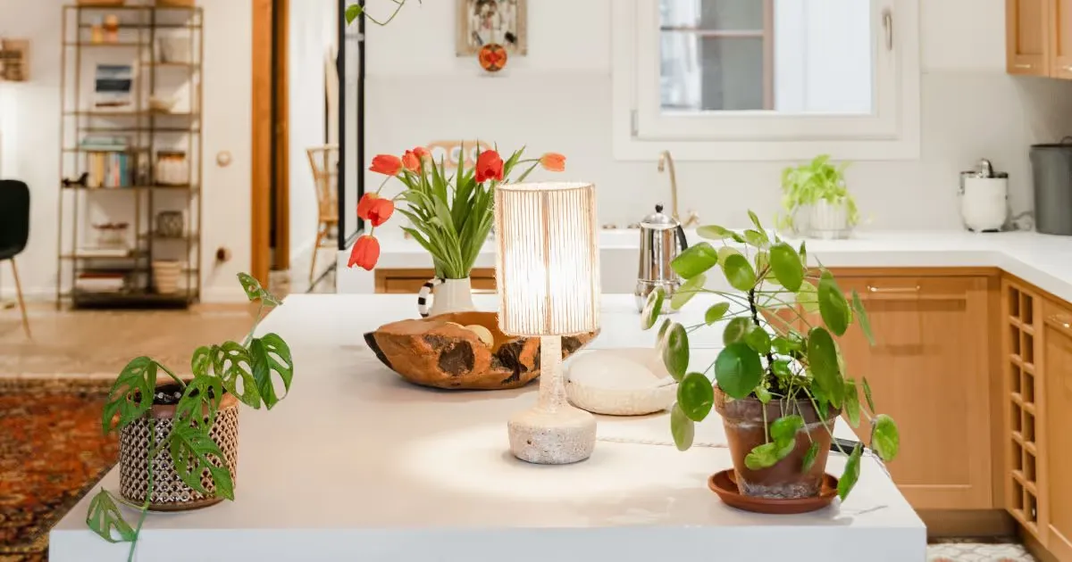 Cozy kitchen workspace with plants, tulips, and a warm lamp, symbolizing a comfortable and productive environment.