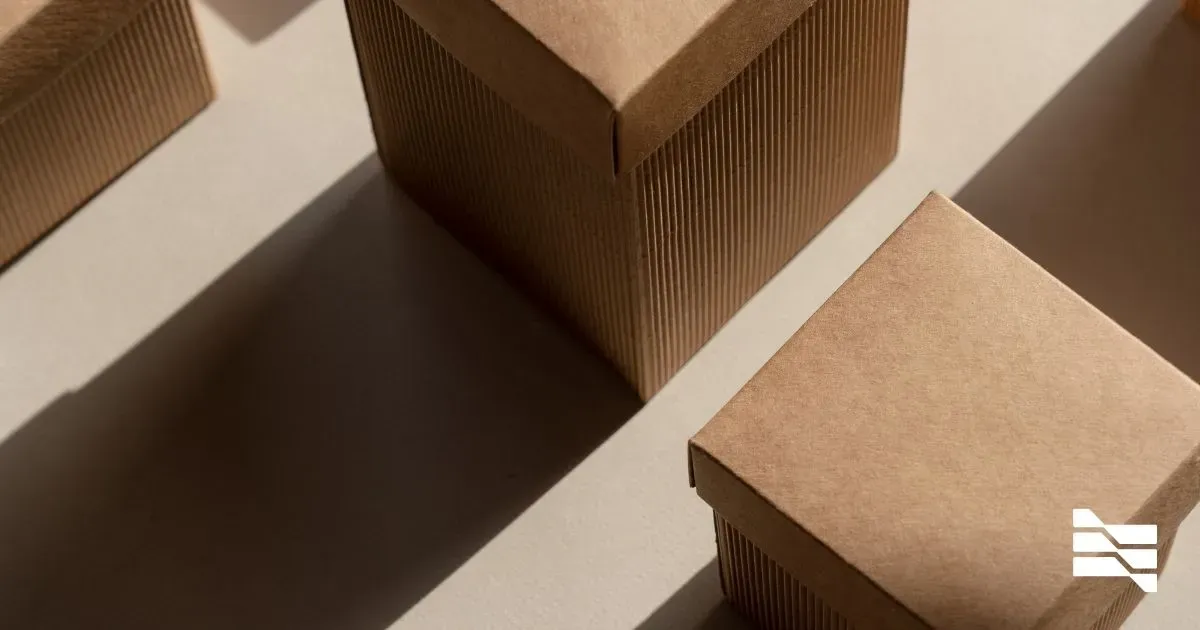 Assorted cardboard boxes casting sharp shadows on a cream surface, a metaphor for organizing and showcasing work on portfolio-building platforms for solo talents.