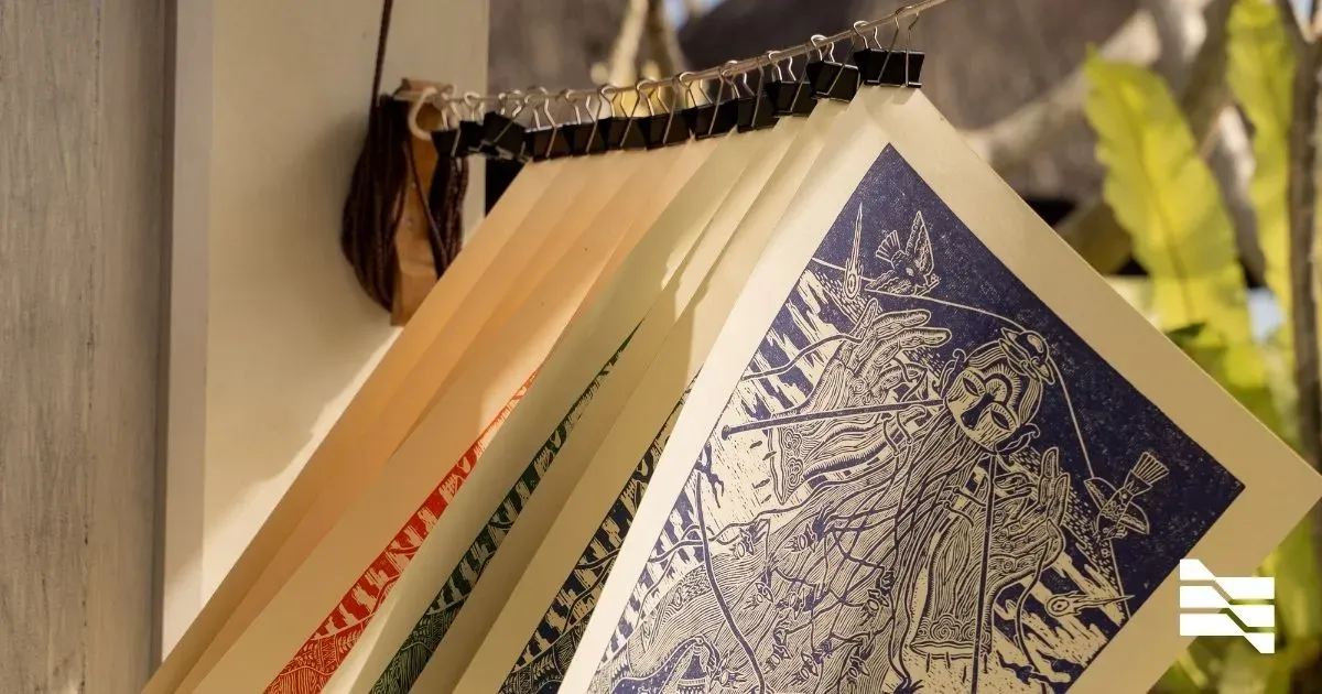 Artistic prints hung on a wall, showcasing intricate blue linocut art, reflecting solo business promotion creativity.